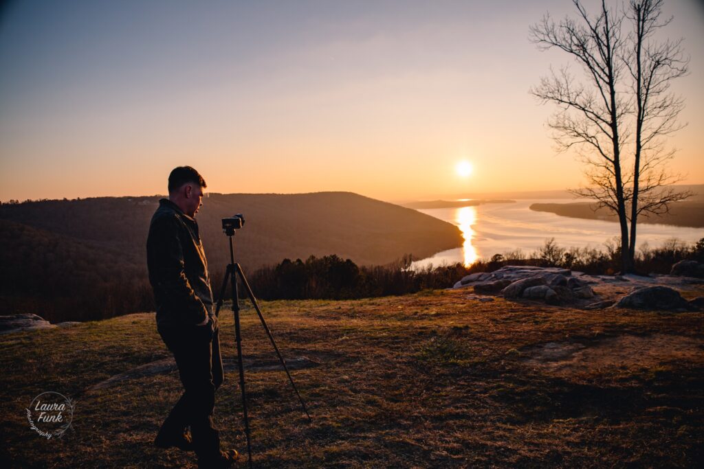 sunset looking over a river with a man looking at his camera