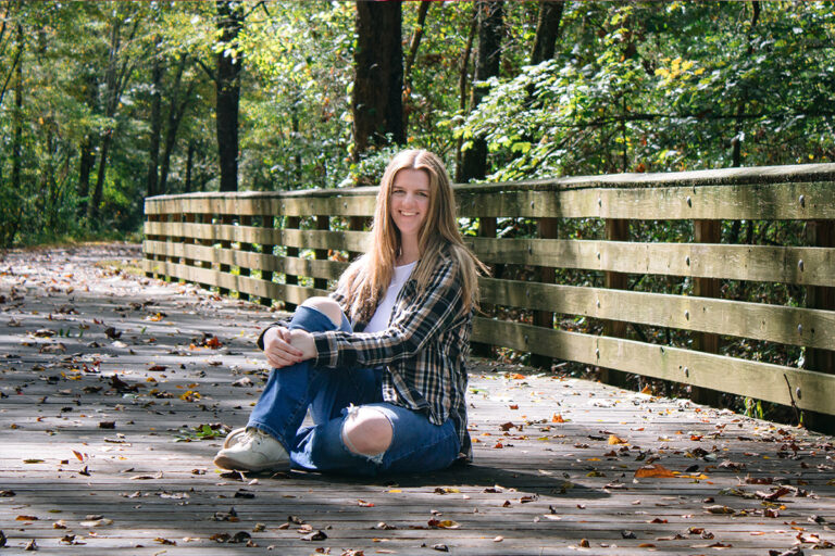 Girl sitting on a bridge in a park posing for a senior photo session