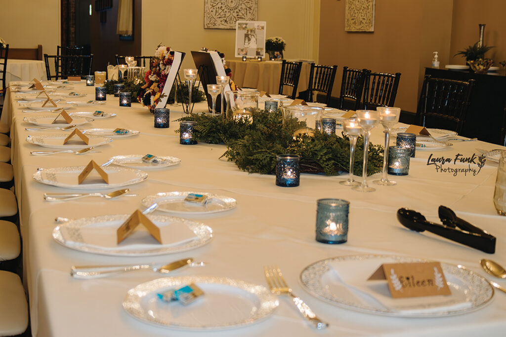 table place settings filled with beautiful greenery centerpieces and white and gold trimmed plates