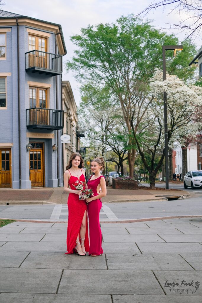 Street view prom pose of two girls in red dresses