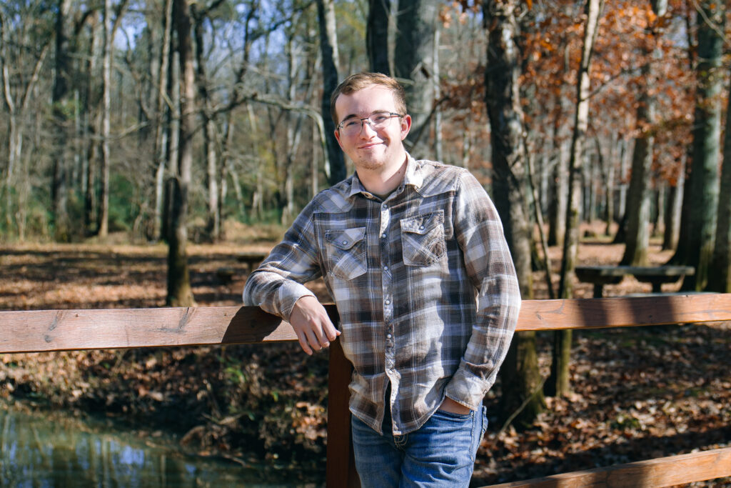 young man leaning on a fence. Portrait for senior photos