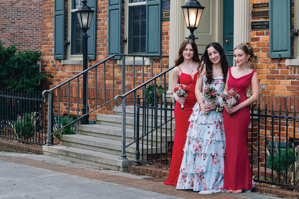 3 girls on prom night together in front of a home.